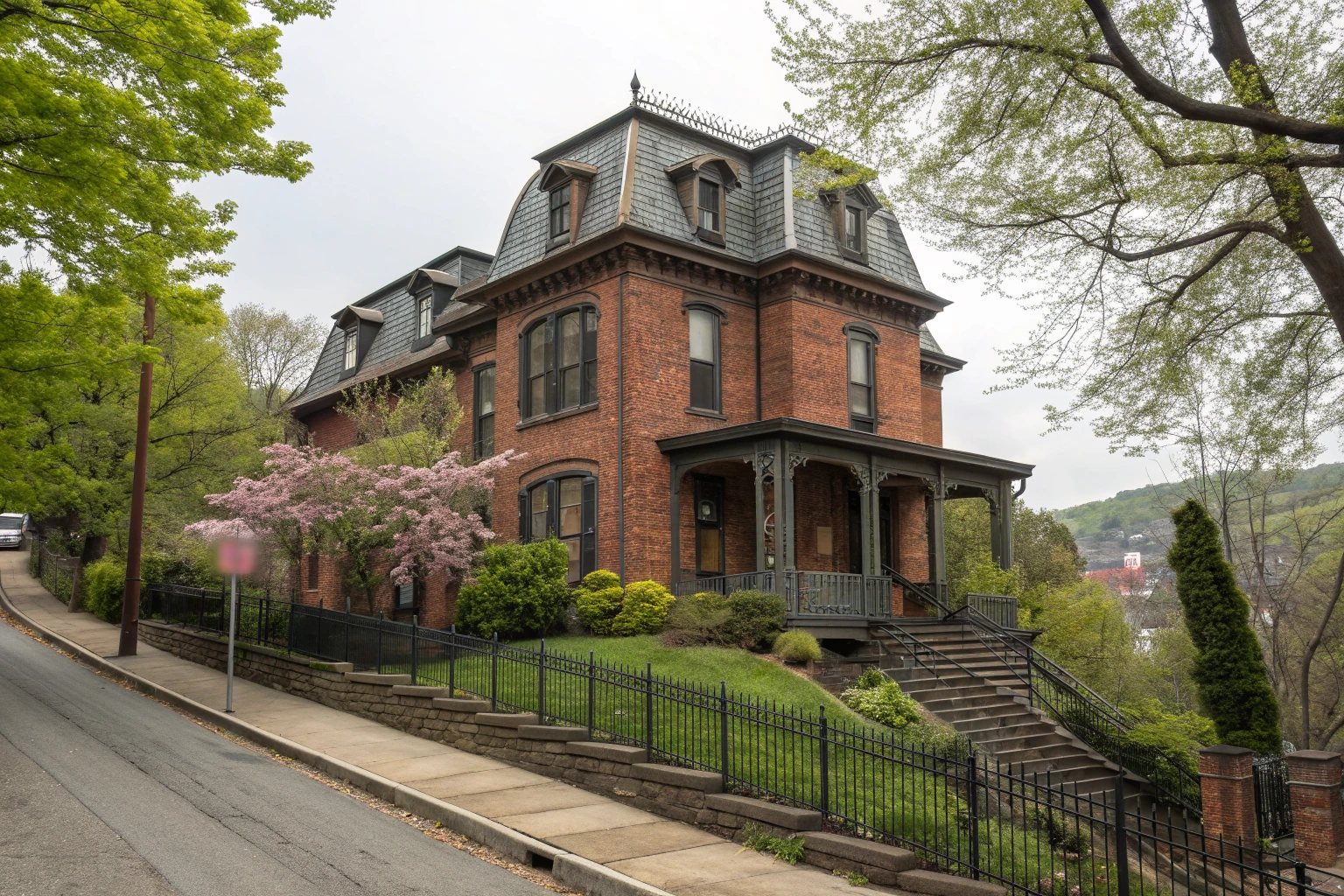 A restored 1870s brick Victorian house with a mansard roof and dormers behind an iron fence